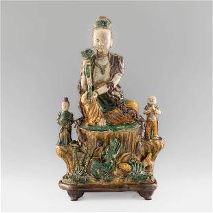 A Chinese sancai sculpture of a buddha, Ming dynasty: A Chinese sancai sculpture of a buddha Ming dynasty Centering a buddha with ruyi scepter raised on a rock formation and seated on lotus leaf, flanked by two devotional figures. Sold with associated wo